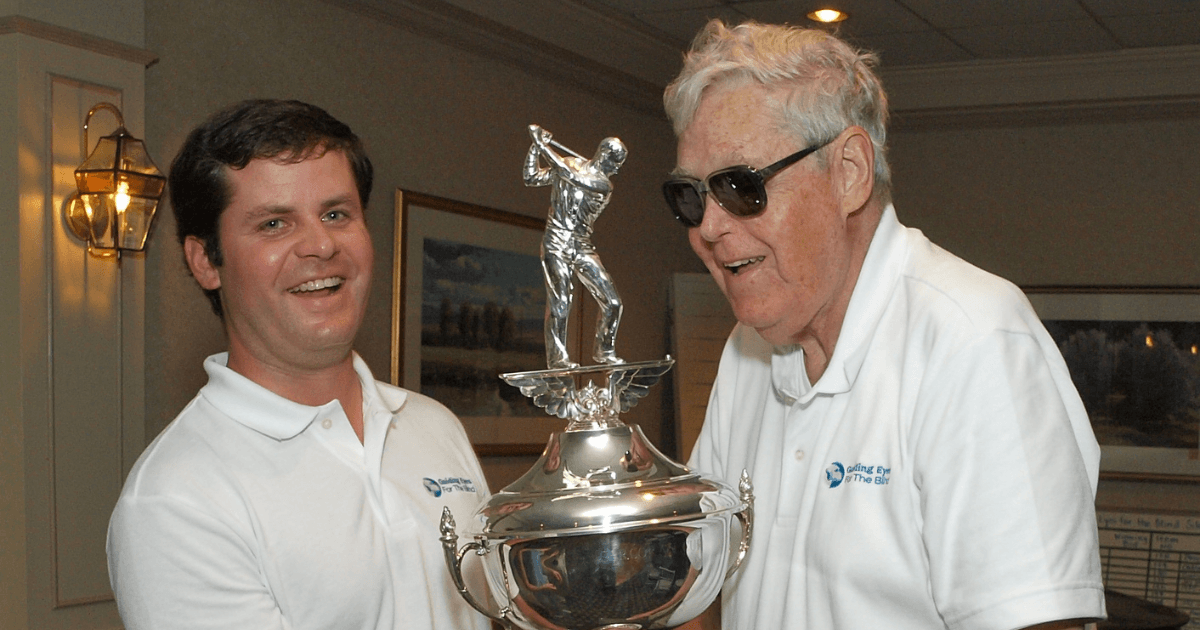Pat Browne III and Pat Browne Jr. hold the Corcoran Cup trophy together at the Guiding Eyes annual golf event.