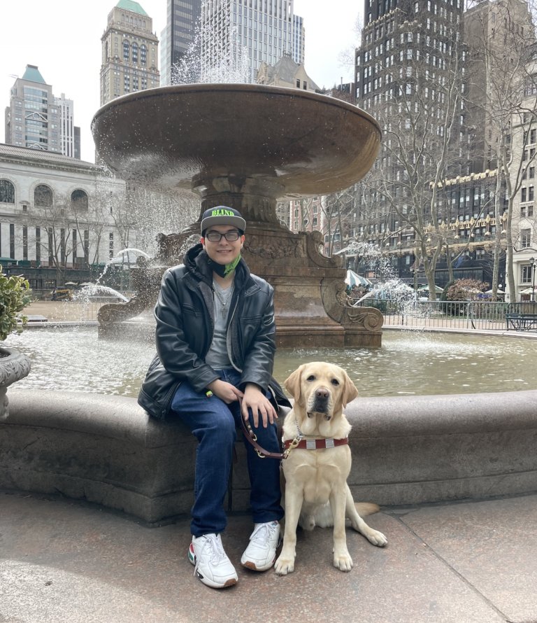 handler and dog sit on edge of Bryant Park fountain