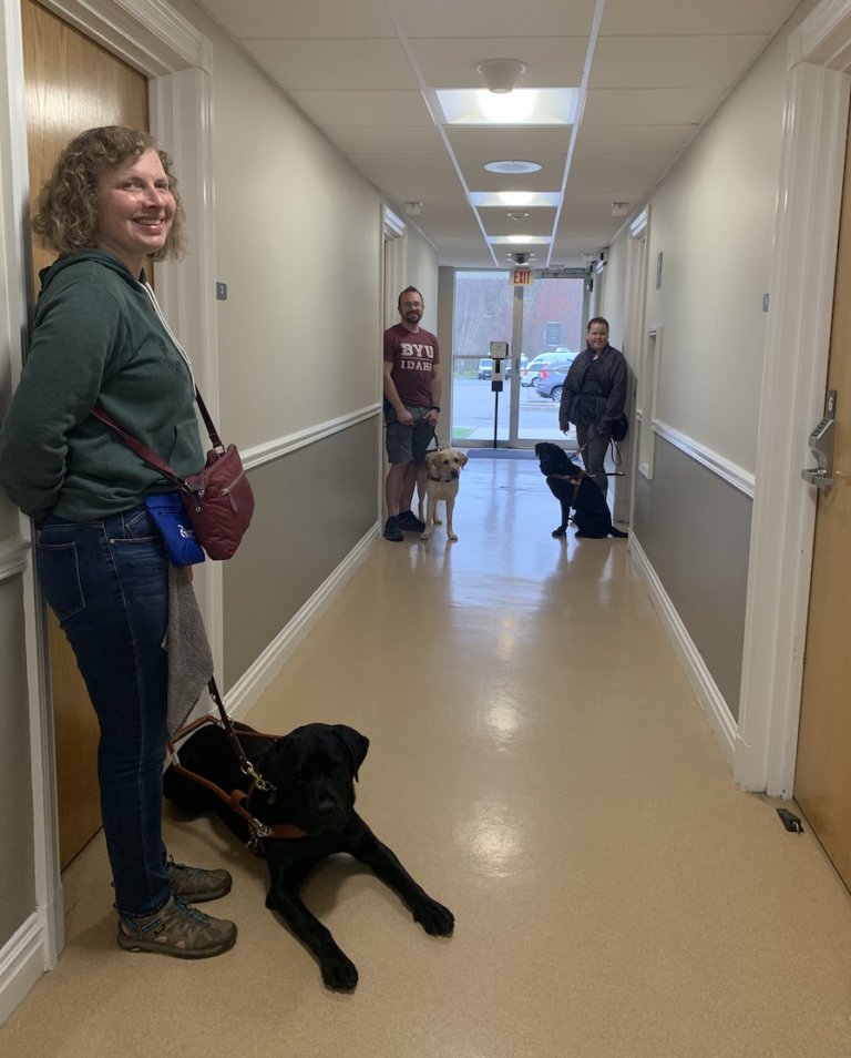 students and dogs stand in dormitory hallway