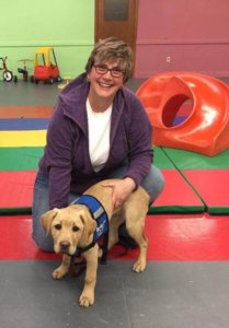 Kari kneels next to Yetta, who just earned her blue Guiding Eyes vest at a walk and talk evaluation