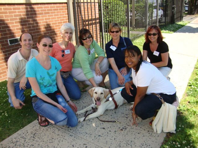 A group of Transvision students poses with a Guiding Eyes guide dog