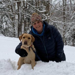 Kari poses in the snow with yellow lab Yetta.