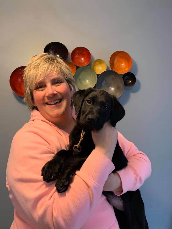 Woman smiling with black lab puppy
