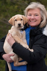 Pictured: Lorraine poses with one of the puppies she has helped raise, a male yellow Labrador named Ed.