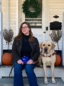 Graduate Amanda sits with Taz on the front step amongst the pumpkins.