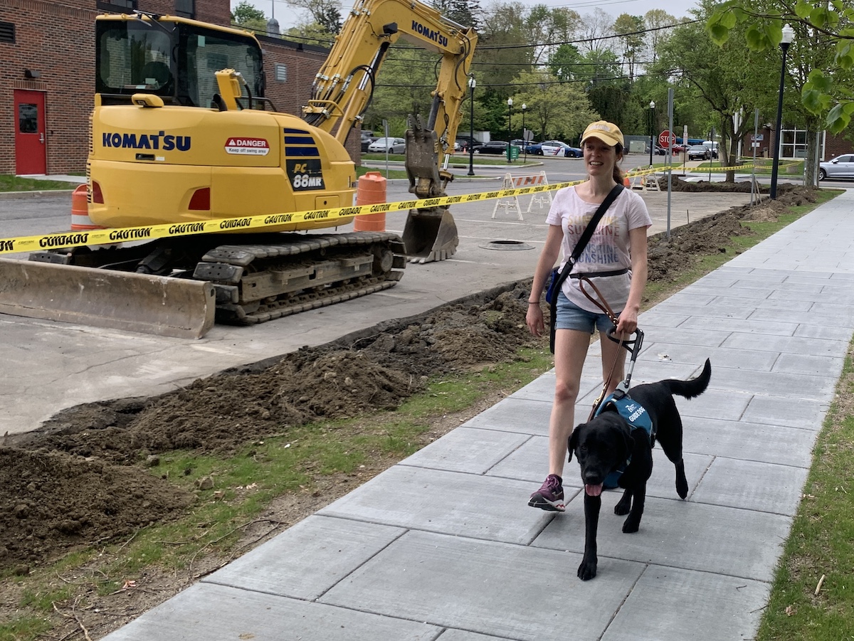 Lolly leads Ashley safely past backhoe and digging near sidewalk