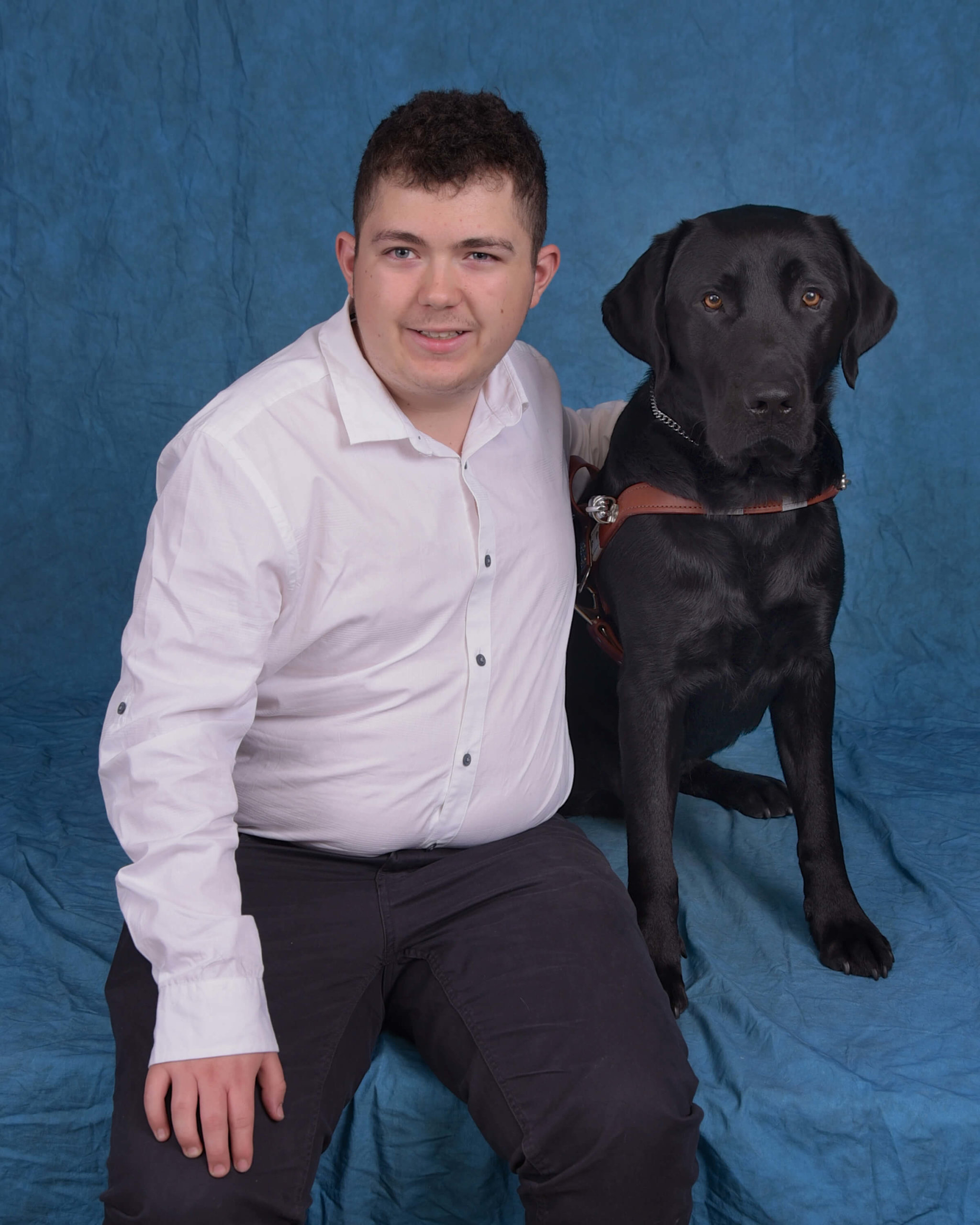 A formal photo of Cody with black lab guide dog Drummer.