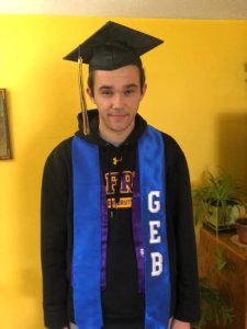 Drew Baginski wears his graduation cap along with a blue stole around his neck which reads, "GEB".