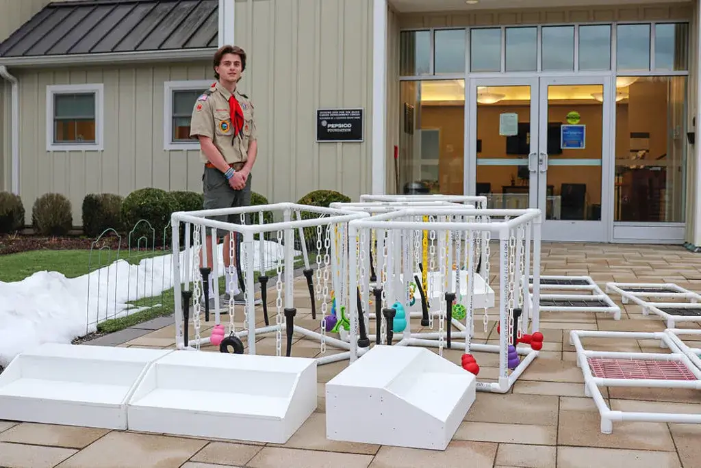 Eagle Scout Garrett Martin stands outside the Canine Development Center in his uniform with his project at his feet.