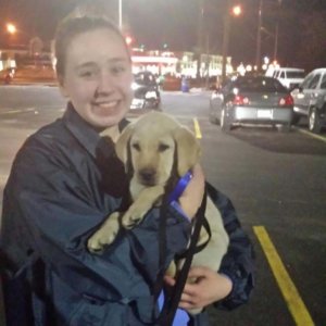 Courtney holds yellow lab puppy Olaf her in arms for the first time while standing in the parking lot.