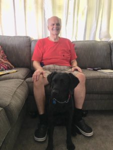 August 2018 graduate David sits on a couch and poses for a photo with guide dog Dottie