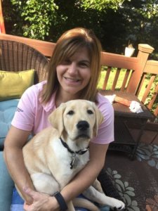 Dawn sits on the porch with adolescent yellow lab puppy Barry on her lap.