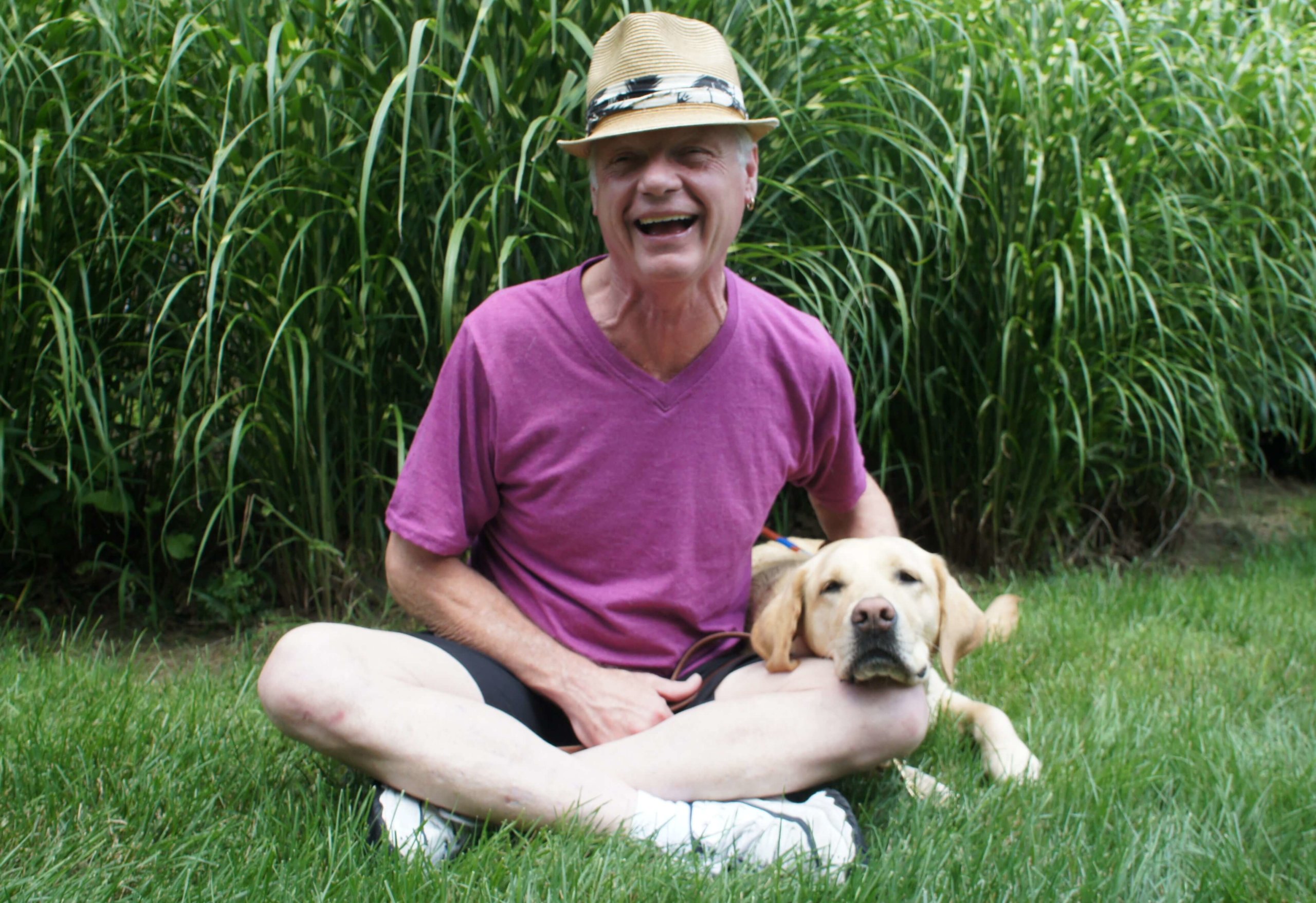 July graduate Doug and guide dog Kimberly sit in the grass together