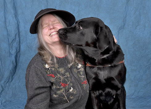 Graduate Judy face to face with black Lab guide dog Orville