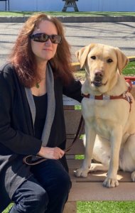 Grad Kara and beautiful Guide Dog Petals sit together on an outdoor bench
