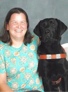 Graduate Leah and guide dog Odell smile for a photo together
