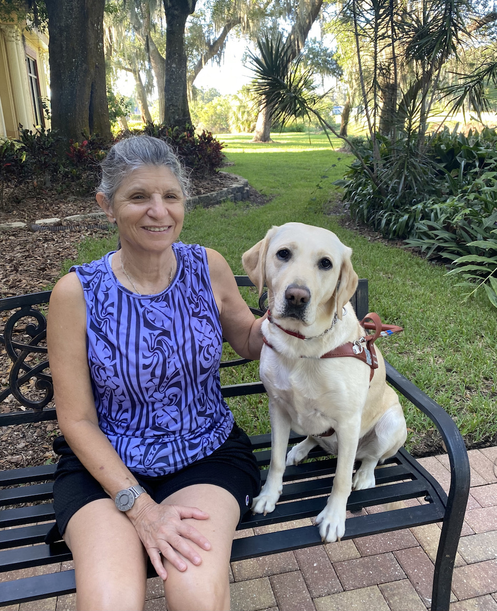 Graduate Linda and guide dog Susie sit on a park bench