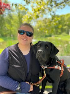 Graduate Lisa happily sits on a bench with her new guide dog Nona