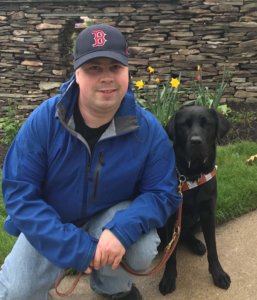 Graduate Michael sits with his guide dog Rufus