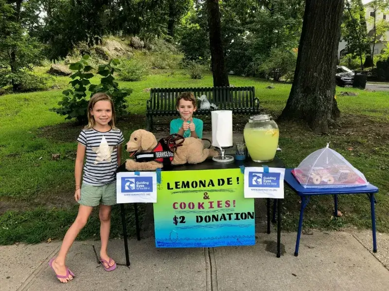 The Mingey children stand next to their lemonade stand at a local train station