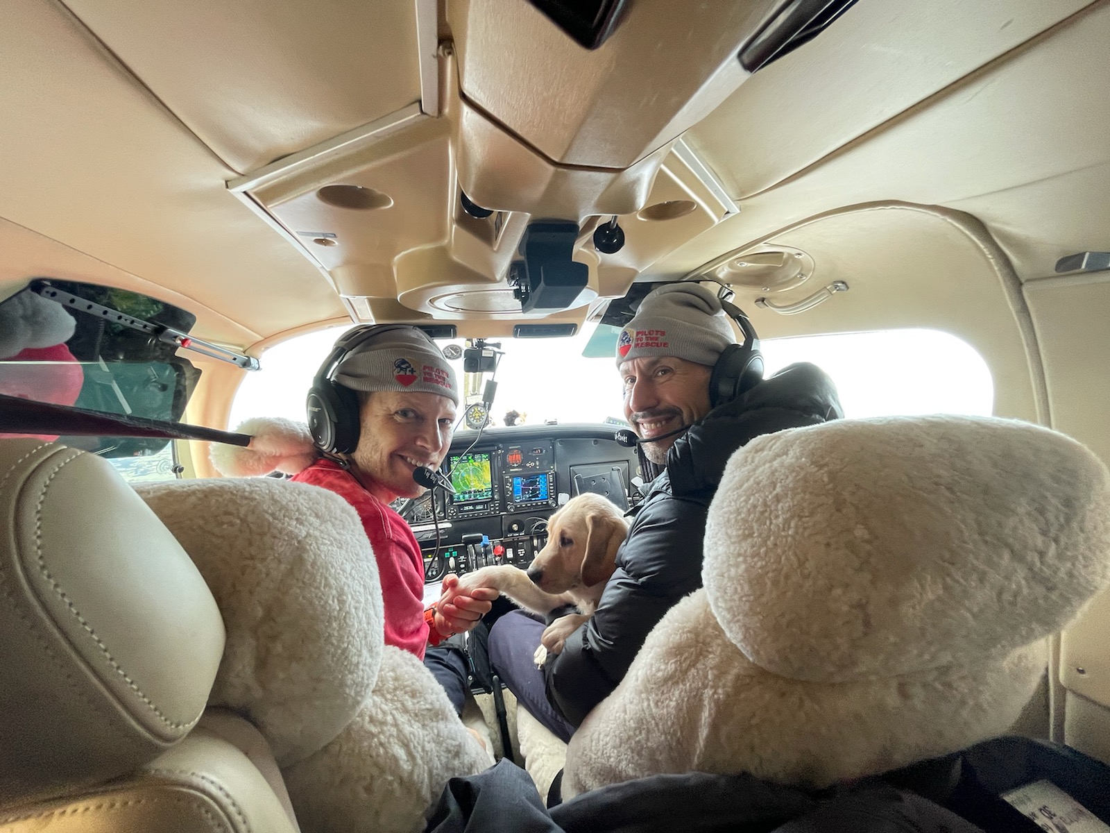 Pilot Michael Schneider and CEO Thomas Panek in cockpit with yellow Lab puppy