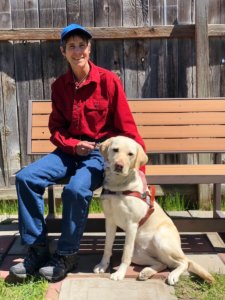 Grad Rhonda and guide Pippi pose together at a wooden bench