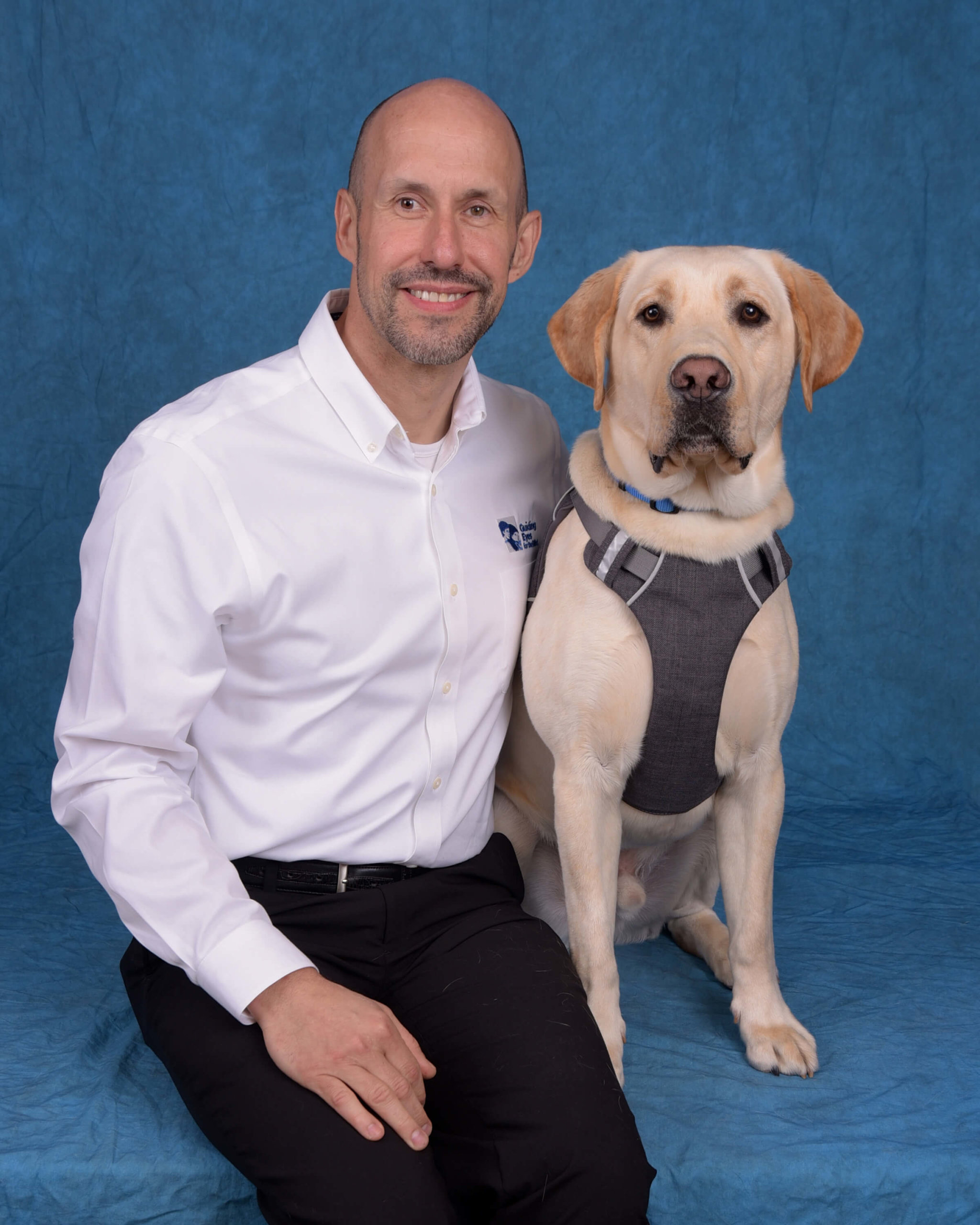 A formal photo of Thomas with yellow lab guide dog Blaze.