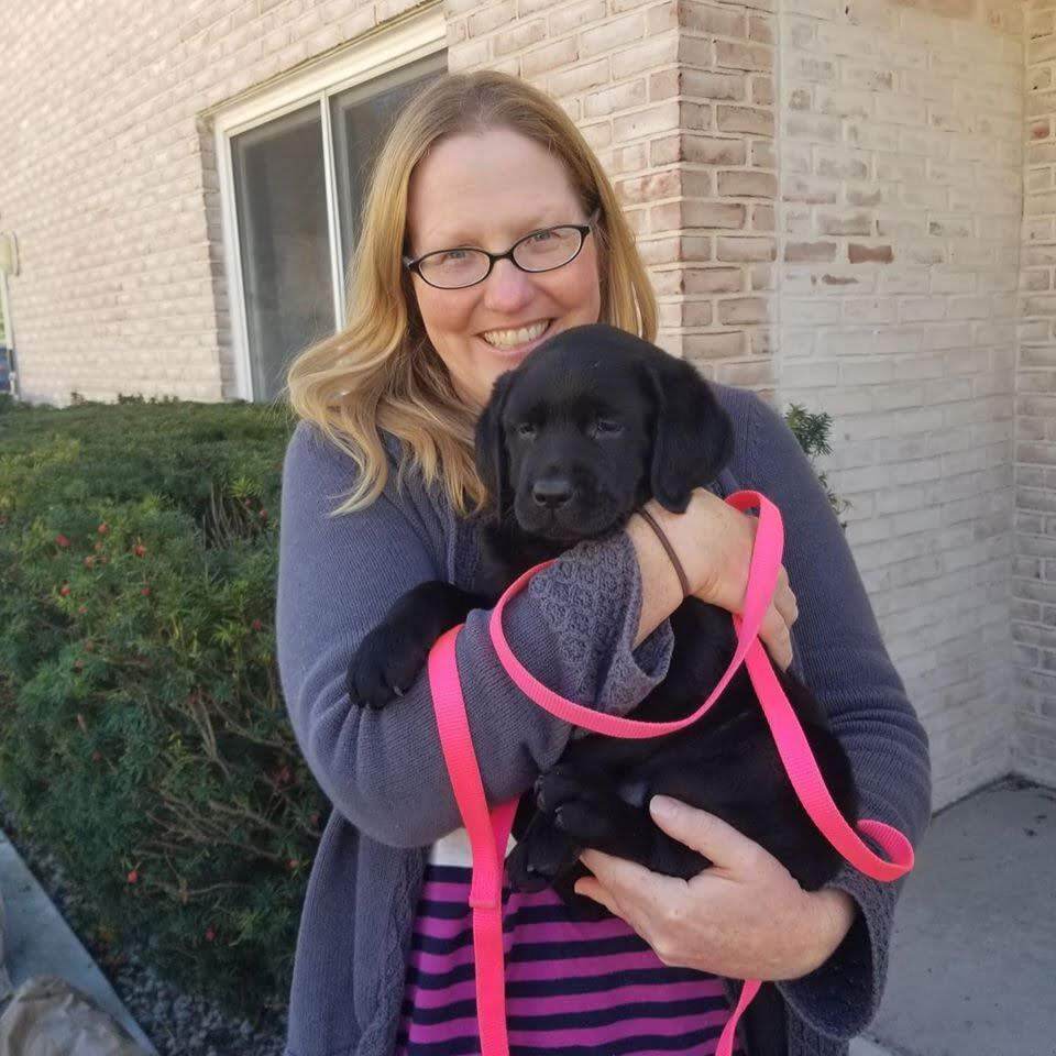 Tara holds her 10th Guiding Eyes pup a black lab puppy named Malinda.