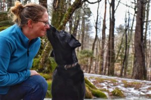 Black lab Flynn gives Tara a kiss on the lips during a quiet moment in the forest.