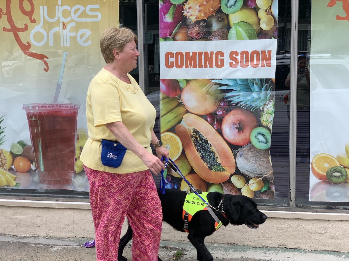 Theresa and Neville pass a storefront with colorful window posters