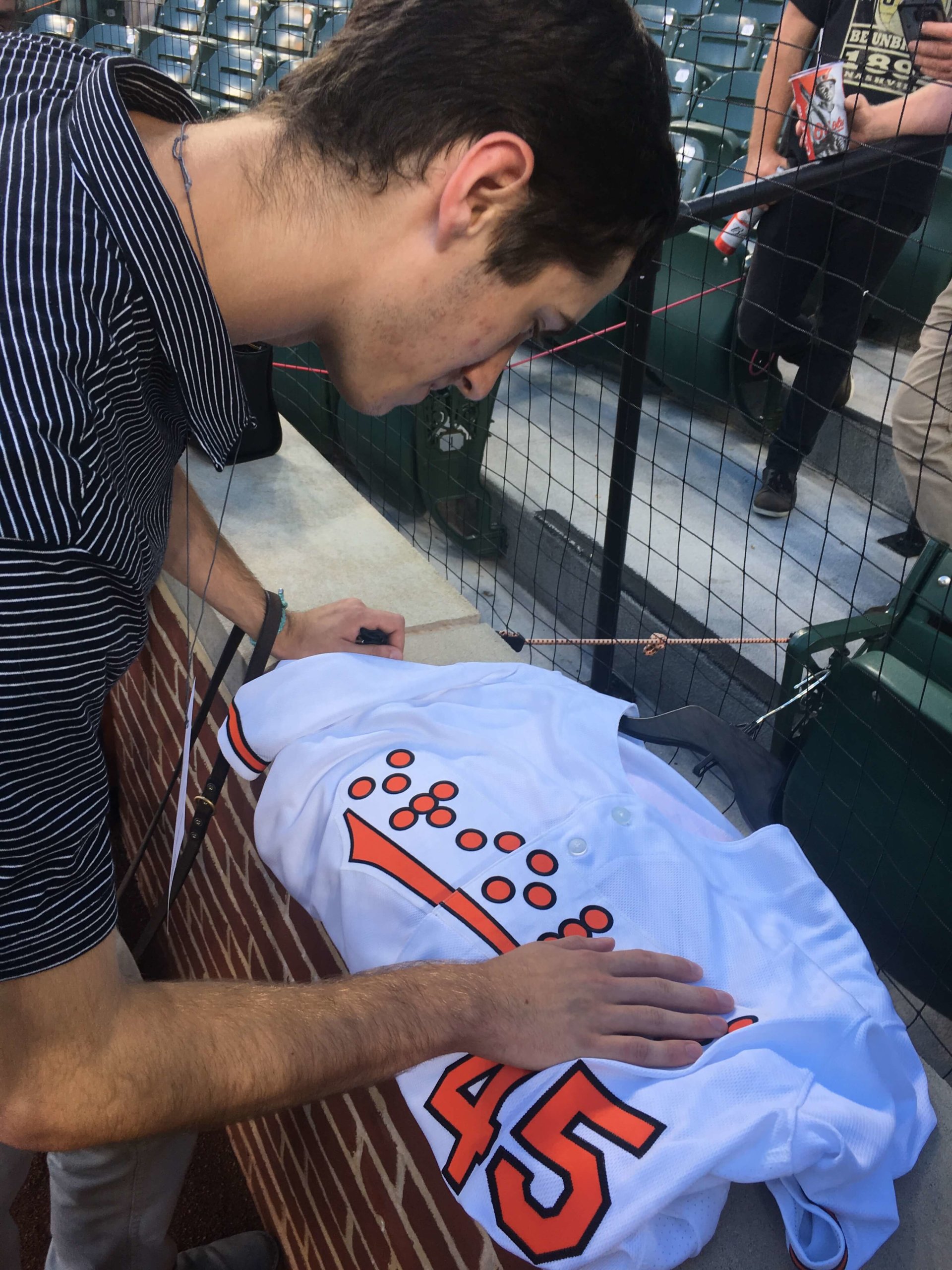 Graduate Tim Utzig reads one of the Braille uniforms worn by the Orioles that night