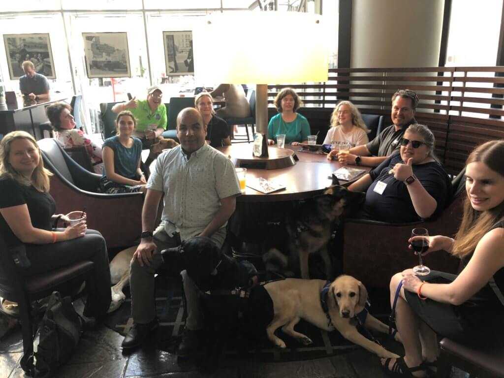 Guiding Eyes staff, Melissa, Ben and Danielle enjoying the company of graduates and their guides around a large round table