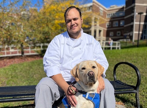 Christian on outdoor bench - yellow Lab Gabe sits between his feet