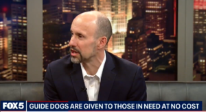 Thomas Panek speaks to the mission of Guiding Eyes with Fox5 chyron at bottom: Guide Dogs are given to those in need at no cost