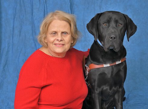 Cindy sits with black lab guide dog for formal portrait