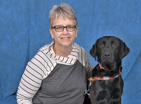 Jaqueline and black Lab guide dog Kathryn sit for their team portrait