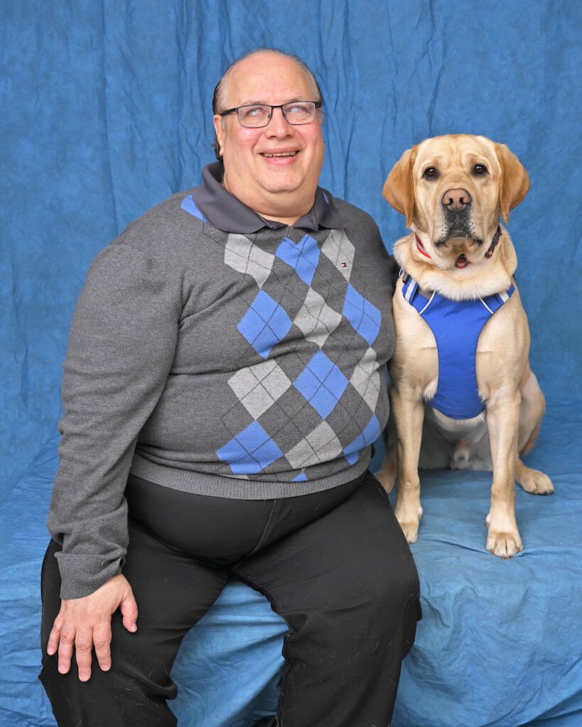 Jose and yellow Lab guide dog in blue harness, pose for team portrait