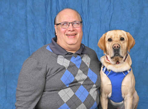 Jose and yellow Lab guide dog in blue harness, pose for team portrait