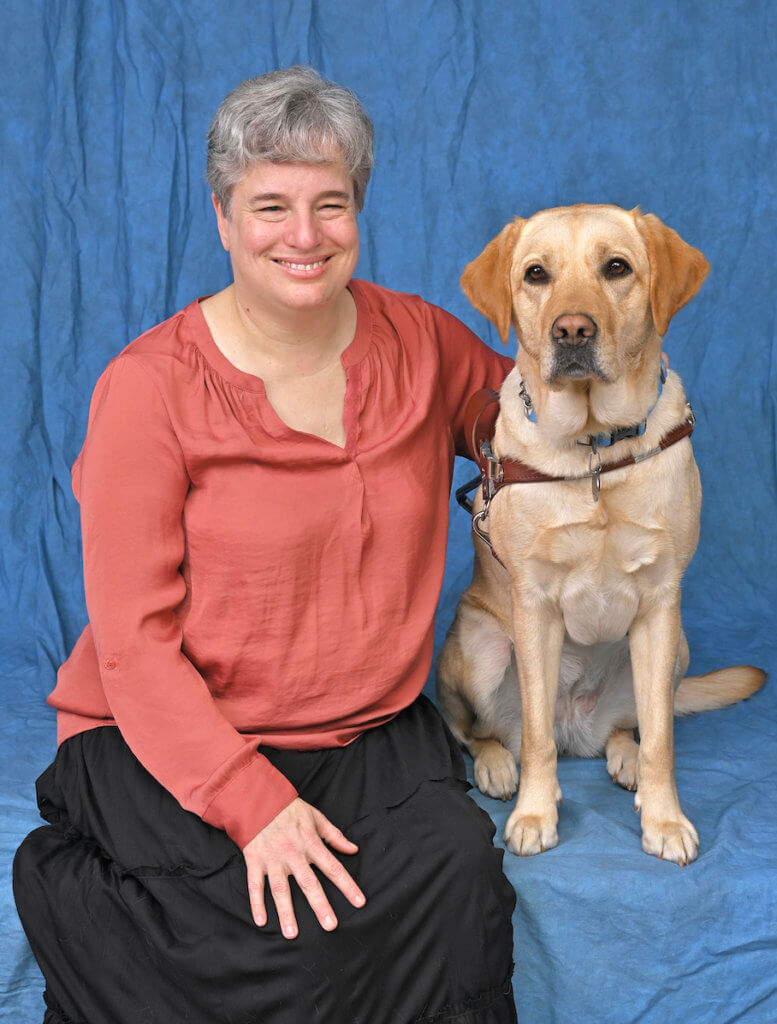 Leslie sits with yellow Lab guide dog Omega in formal portrait