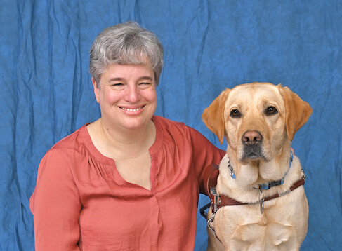 Leslie sits with yellow Lab guide dog Omega in formal portrait