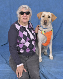 Margaret and yellow lab guide dog Happy sit for their graduate portrait