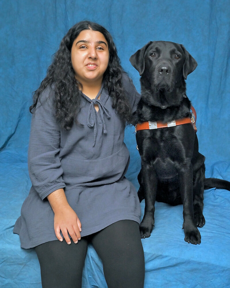 Fatima and black Lab guide dog Miles sit for their formal portrait