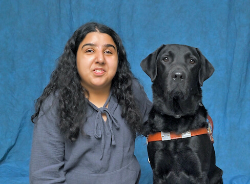 Fatima and black Lab guide dog Miles sit for their formal portrait