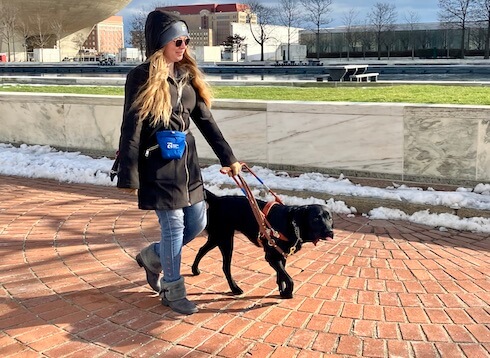 Michaela walks safely on brick sidewalk with guide Eleanor