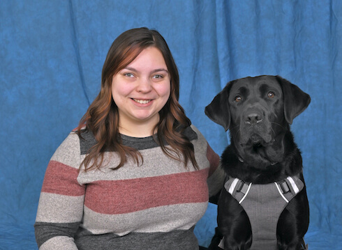 Apryl and black lab guide Harmony sit for the team portrait