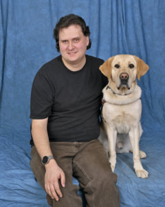 Drew and yellow Lab guide dog Crew sit for team portrait
