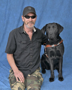 Richard and black Lab guide Shamrock sit for their graduate portrait