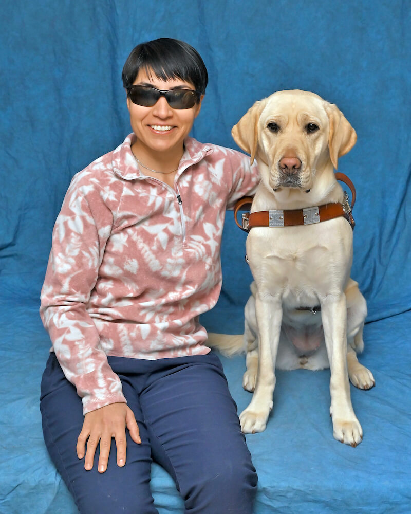 Samaneh and yellow guide dog Lemon, sit for their graduate portrait