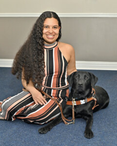 Christina and black Lab guide dog Acadia sit in relaxed pose for team portrait