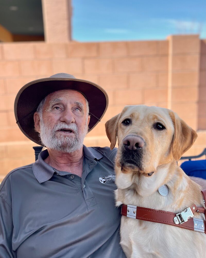 Dick and yellow guide dog Presley sit for team portrait
